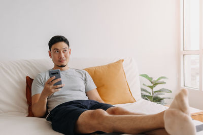 Portrait of young man sitting on bed at home