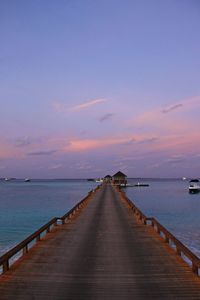 Pier over sea against sky during sunset