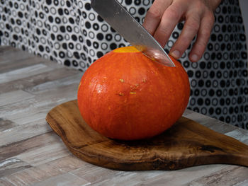 Close-up of hand holding orange on cutting board