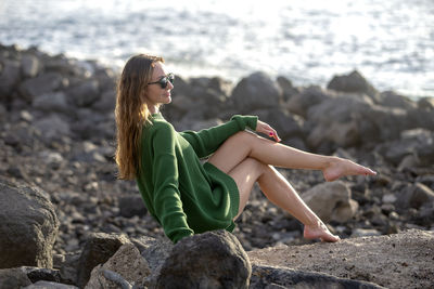 Beautiful woman sitting on rock at beach