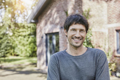 Portrait of smiling man in front of his home