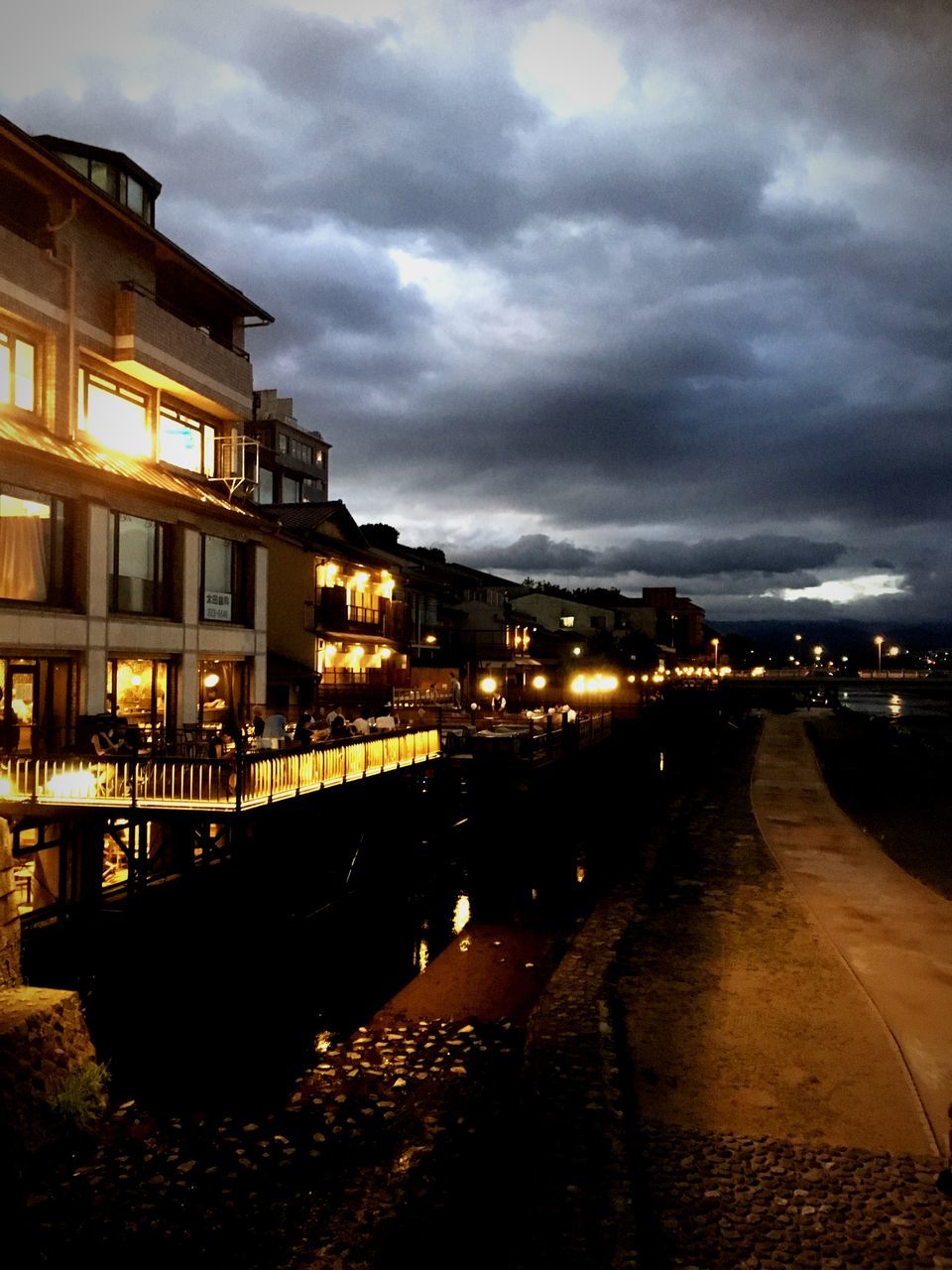 ILLUMINATED STREET AMIDST BUILDINGS AT NIGHT