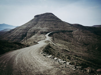 Dangerous dirt road leading towards mountain against sky in arid landscape of lesotho, africa