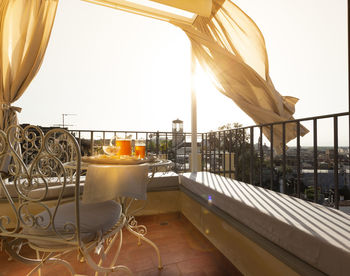 Table and chairs in balcony against sky
