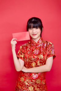 Portrait of a smiling young woman against red background