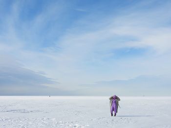 Rear view of woman walking at beach against sky