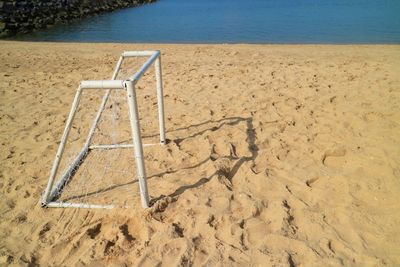 Mini soccer goal on the beach with blue sea and sand in the summer.