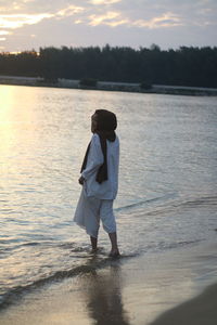 Rear view of man standing on beach during sunset