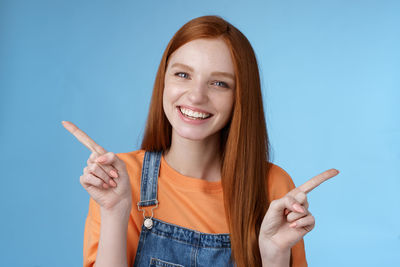 Portrait of a smiling young woman against blue background