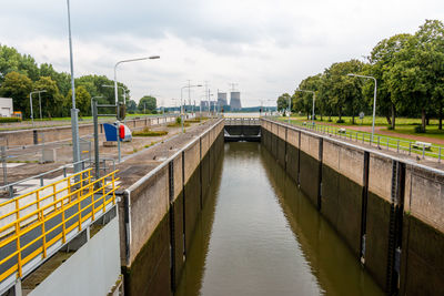 View of a sluice in the river the maas with in the background the powerplant of the city of roermond