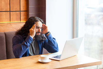 Woman using mobile phone while sitting on table