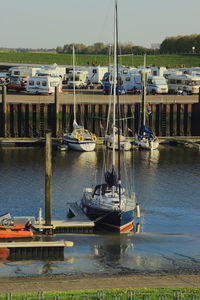 Sailboats moored on sea against sky