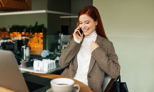 Young woman using mobile phone while sitting on table