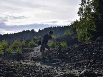 Man standing by tree in forest against sky