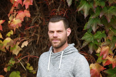 Portrait of young man with leaves against plants