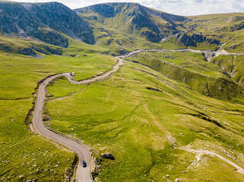 Winding road from high mountain pass, in summer time. aerial view by drone . romania