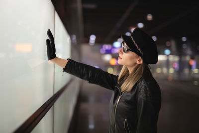 Portrait of woman standing against illuminated wall