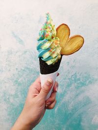 Cropped hand of woman holding ice cream against wall