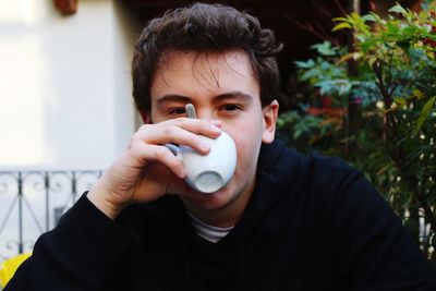 Portrait of young man drinking coffee at backyard