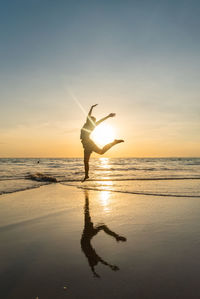 Silhouette man on beach by sea against sky during sunset