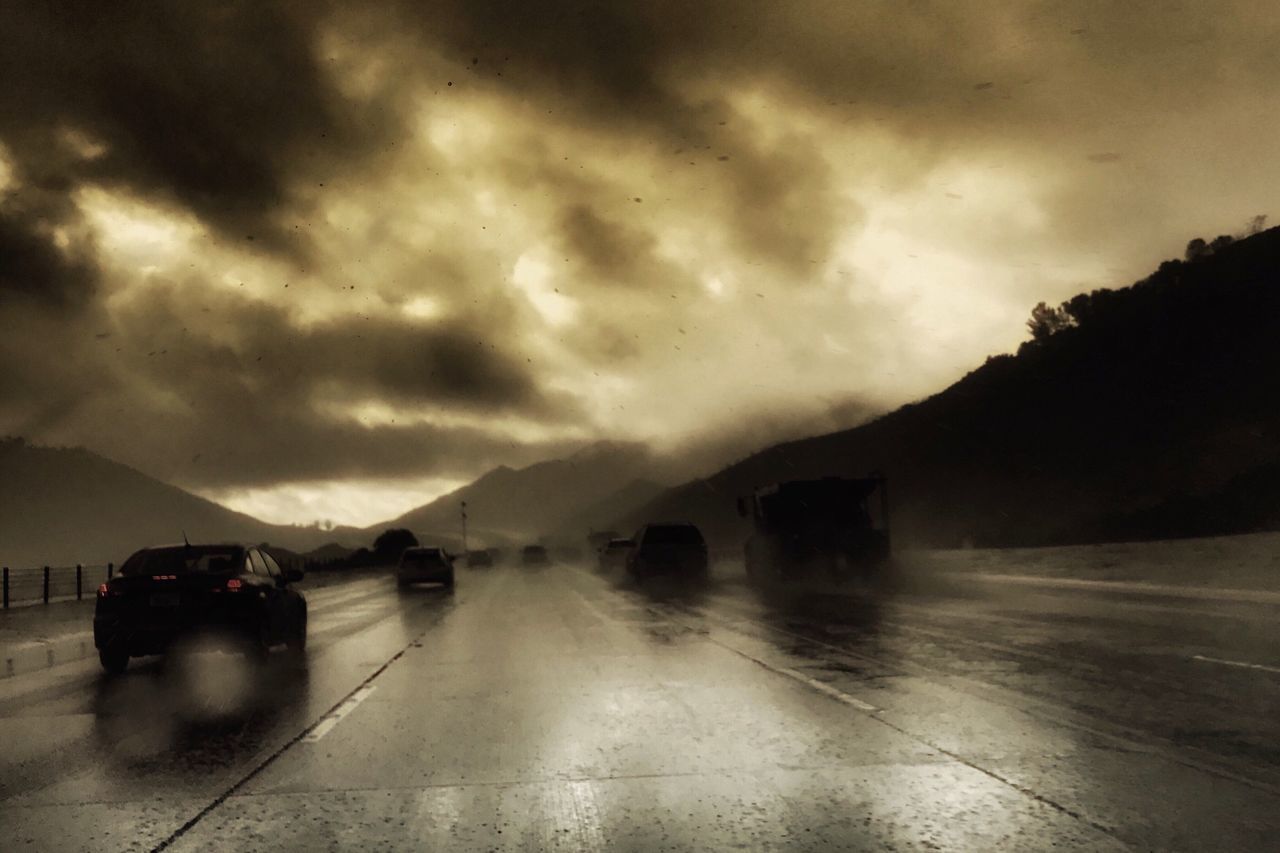 CARS ON WET ROAD AGAINST CLOUDY SKY