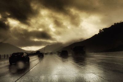 Cars on wet road against sky