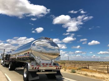 Vehicles on road against sky in city