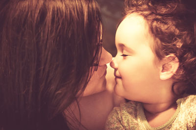 Loving mother and daughter touching noses while showing affection to each other.