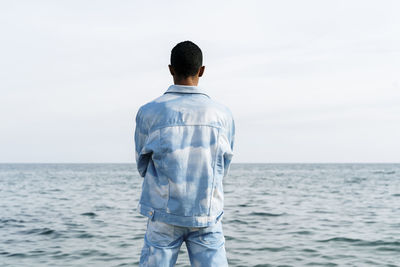 Rear view of man looking at sea against sky