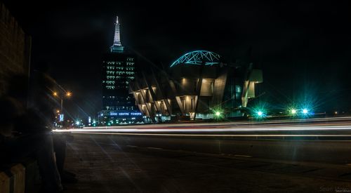 Light trails on road against buildings at night