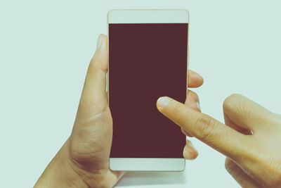 Close-up of hand holding mobile phone against white background