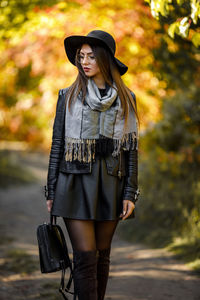 Young woman wearing hat walking in park