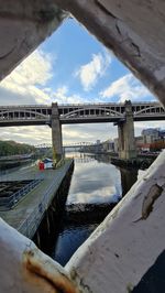 Bridge over river in city against sky