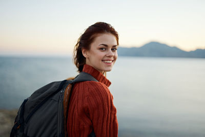 Portrait of smiling young woman against sea against sky