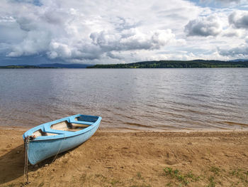 Boat moored on beach against sky