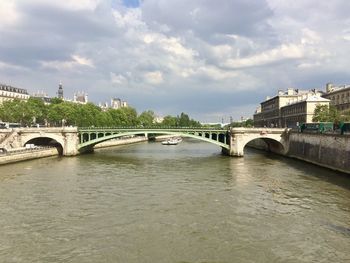 Bridge over river in city against sky