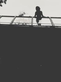 Low angle view of silhouette woman playing by swimming pool against sky