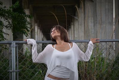 Seductive woman holding chainlink fence