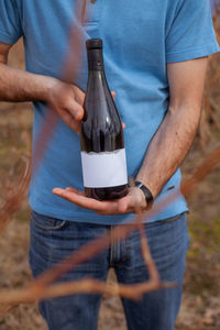 Man holding bottle of wine in hands at the vineyard