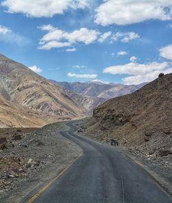 Road leading towards mountains against sky