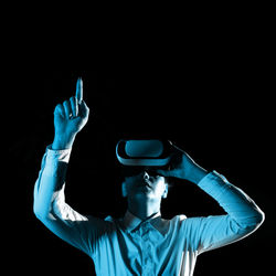 Rear view of man with arms raised against black background