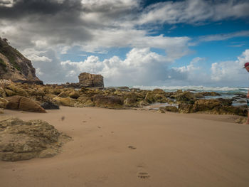 Rock formations on beach against sky