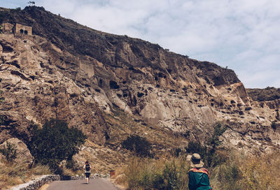 Rear view of people on road by mountain against sky