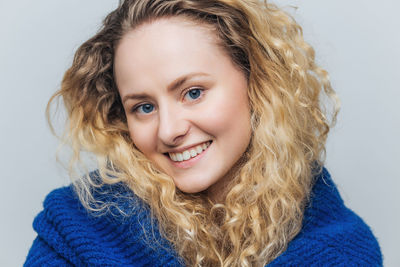 Portrait of young woman against blue background