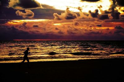 Silhouette of people on beach at sunset