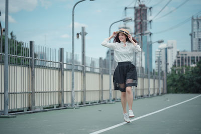 Full length of woman standing by railing against sky