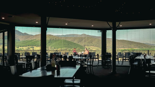 Empty chairs and tables in restaurant against window