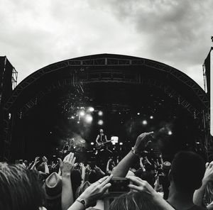 People enjoying music concert against sky