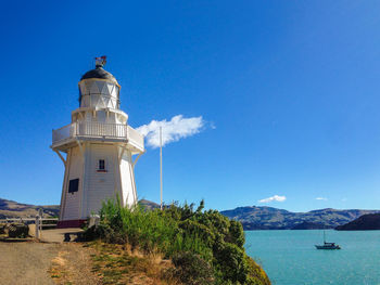 Lighthouse by sea against sky