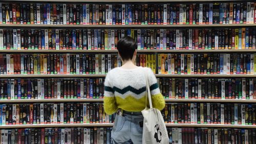 Rear view of woman standing in shelf